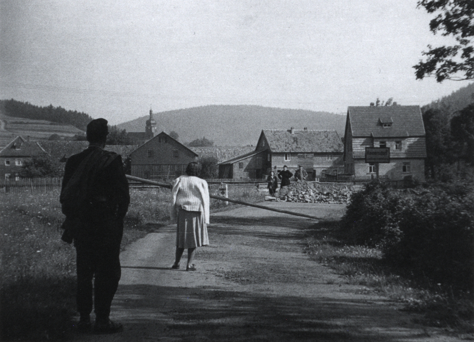 Blick von der oberfränkischen Gemeinde Welitsch (Lkr. Kronach) zur thüringischen Gemeinde Heinersdorf über eine provisorische Straßensperrung aus Bauschutt. Aufnahme unbekannten Datums, wahrscheinlich von Ende Mai/Juni 1952. Als Reaktion auf die Verhandlungen über die EVG und die Unterzeichnung des Generalvertrags durch die Westalliierten und die Bundesregierung hatte die DDR am 26. Mai 1952 die Abriegelung der innerdeutschen Grenze und die Errichtung eines Sperr- und Schutzstreifens angeordnet. Neben der Einstellung des kleinen Grenzverkehrs bedeutete dies auch die Unterbrechung des Eisenbahnverkehrs und von Strom- und Wasserlieferungen. Ab Sommer 1952 erfolgte die hermetische Schließung der Grenze durch die DDR durch Stacheldraht und sonstige Sperranlagen.<br/>Nachweis: Kreisdokumentationsstelle des Landkreises Kronach, Fotosammlung Nr. 14.7./176.