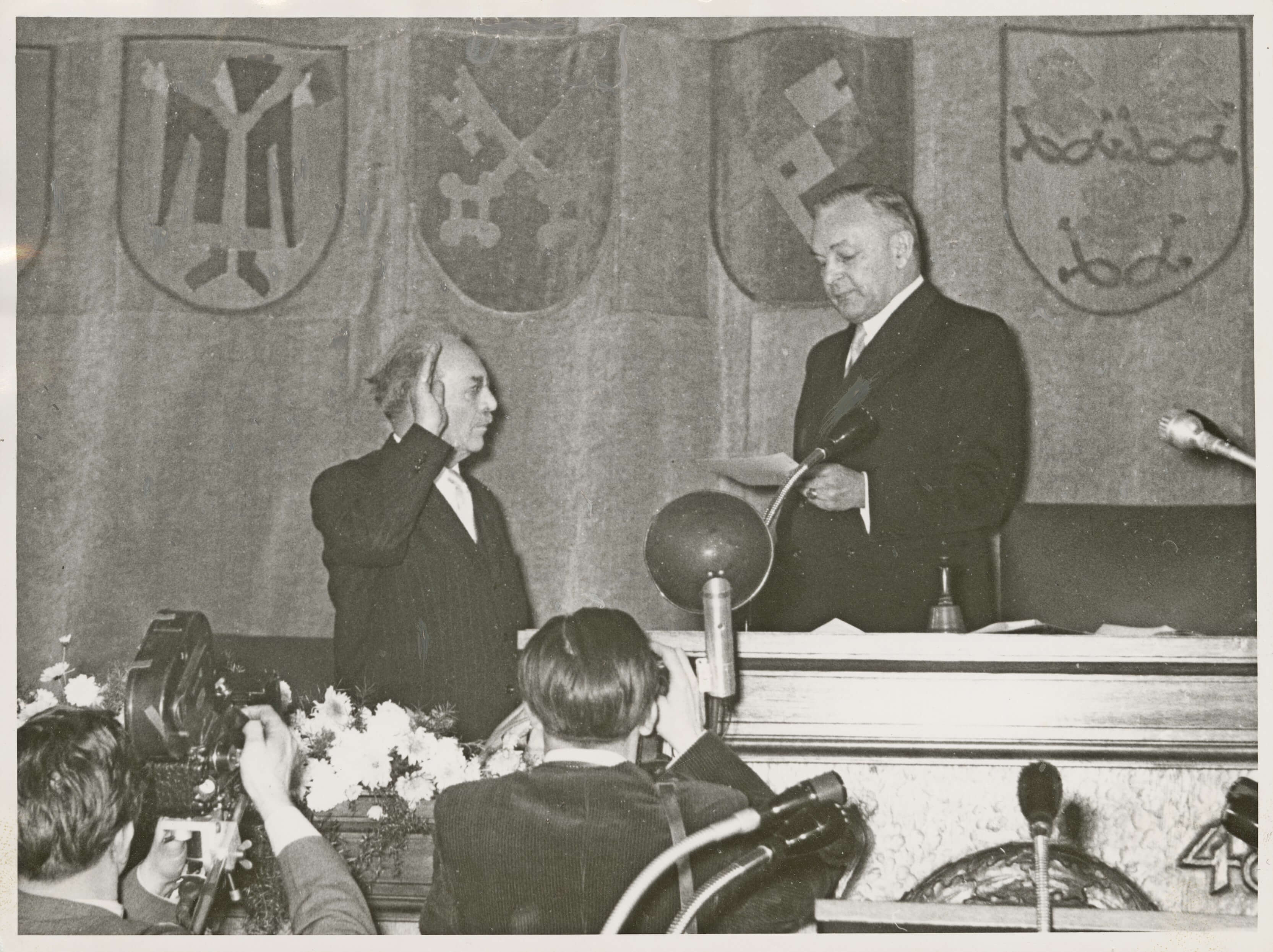 Die Vereidigung des neuen Ministerpräsidenten Wilhelm Hoeger durch den alten Minister- und neuen Landtagspräsidenten Hans Ehard in der Sitzung des Bayerischen Landtags vom 14. Dezember 1954. Hoegner war vom Parlament mit 112 von 197 gültigen Stimmen zum Ministerpräsidenten gewählt worden.<br/>Nachweis: StK-Fotos 115