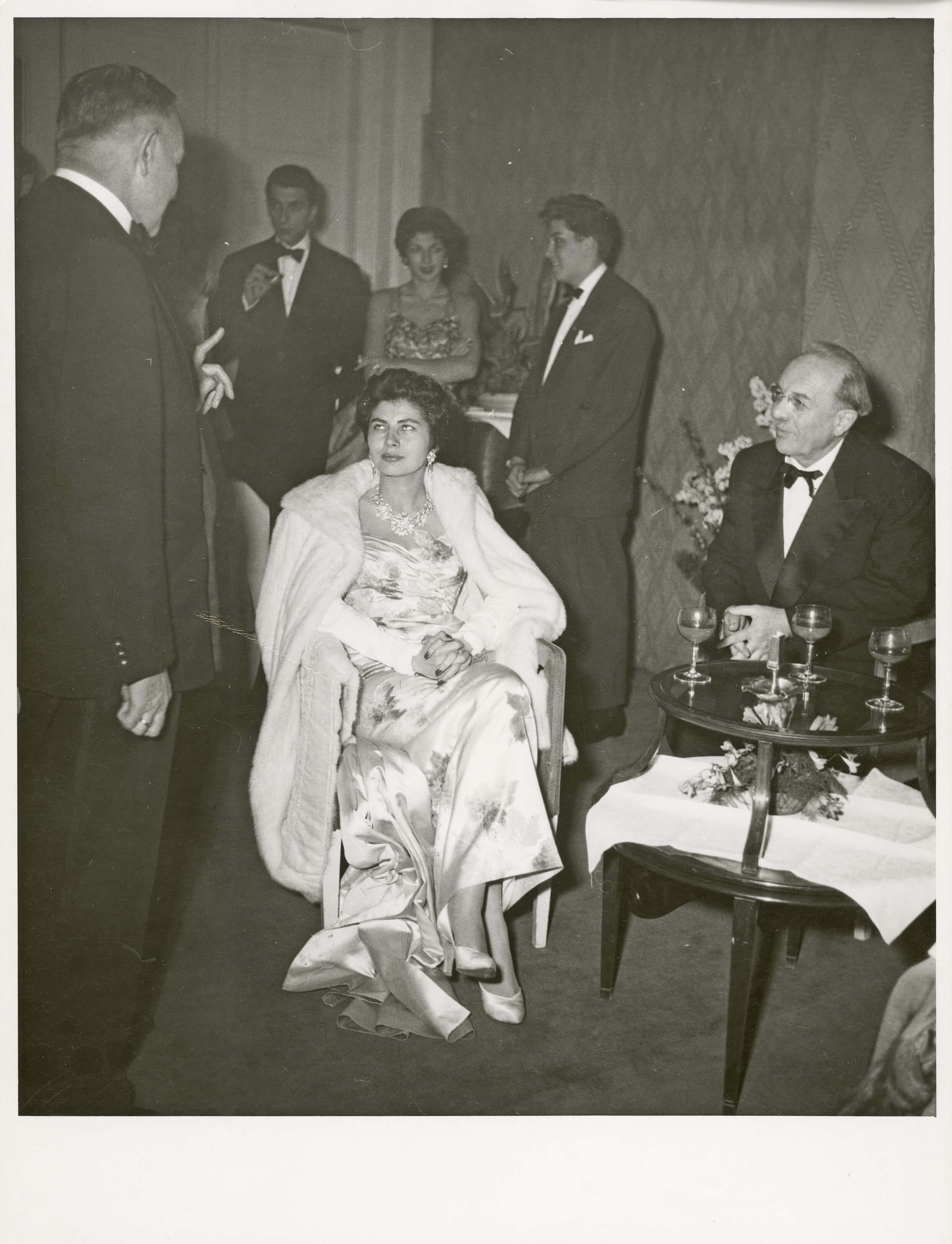 Vom 6. bis zum 10. Oktober 1955 weilte das persische Kaiserpaar in München. Obwohl dieser Besuch als inoffiziell und privat galt, sorgte die Staatsregierung für ein feierliches Rahmenprogramm mit Staatsbankett und einem Opernabend. Das Bild zeigt die Kaiserin Soraya zwischen Landtagspräsident Hans Ehard und Ministerpräsident Wilhelm Hoegner am 9. Oktober 1955 in der Bayerischen Staatsoper. Auf dem Programm stand Mozarts „Entführung aus dem Serail“.<br/>Nachweis: StK-Fotos 119/5